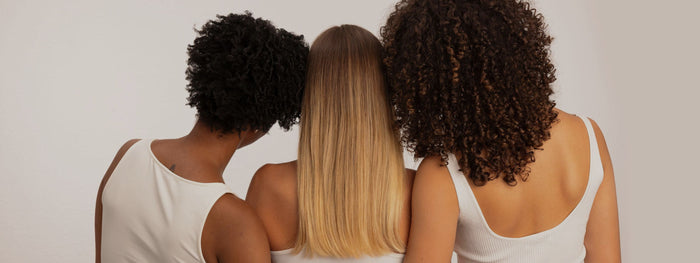Trois femmes de dos aux cheveux crépus, lisses et bouclés : chaque type de cheveux a sa routine